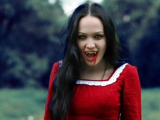 Девушка вампир в красном платье с клыками